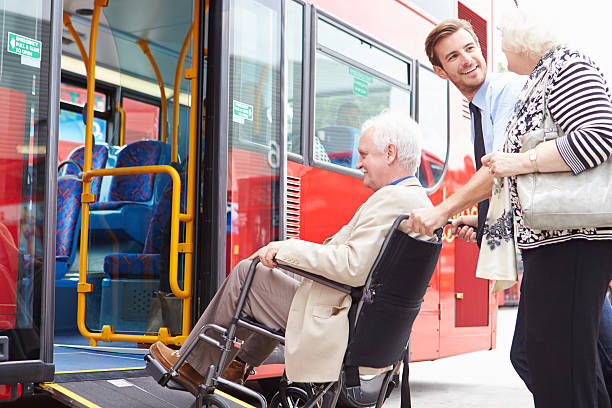 Driver Helping Elderly Senior Couple Board Public Bus Via Wheelchair Ramp